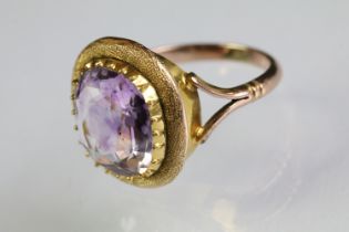 Amethyst solitaire ring being set with an oval mixed cut amethyst within a textured mount raised