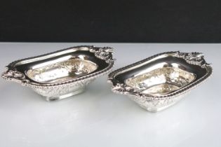 Pair of late Victorian heavy silver salt cellars, with repousse scrolling decoration and cast
