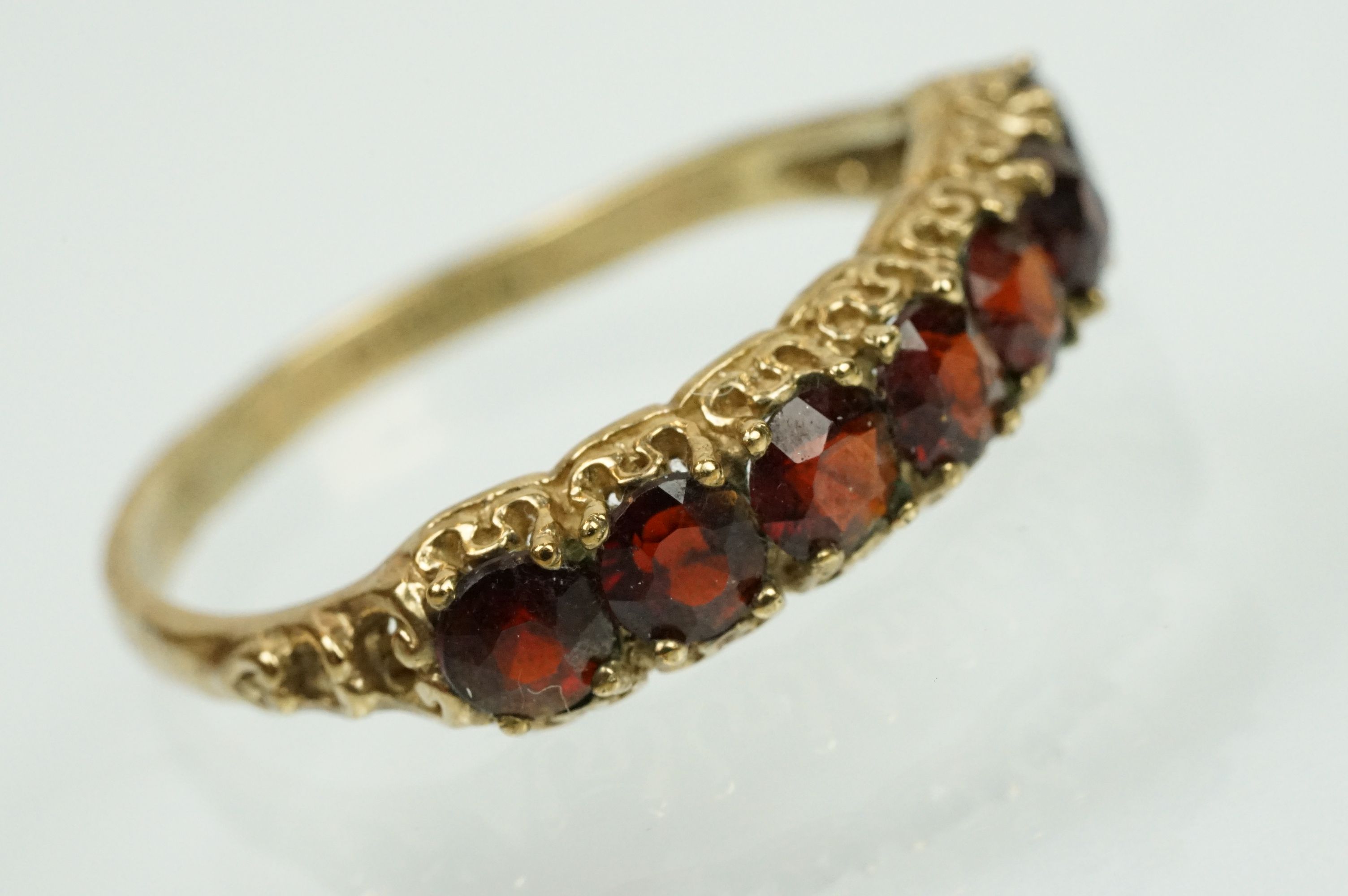 9ct gold and garnet seven stone ring set with seven round cut garnets to a plain shank. Hallmarked