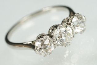 Three stone diamond and platinum ring. The ring being set with three round old cut diamonds in prong