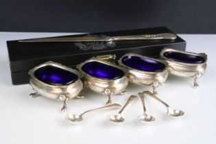 Set of four George VI silver salt cellars, with shaped upper rims and blue glass liners, each raised