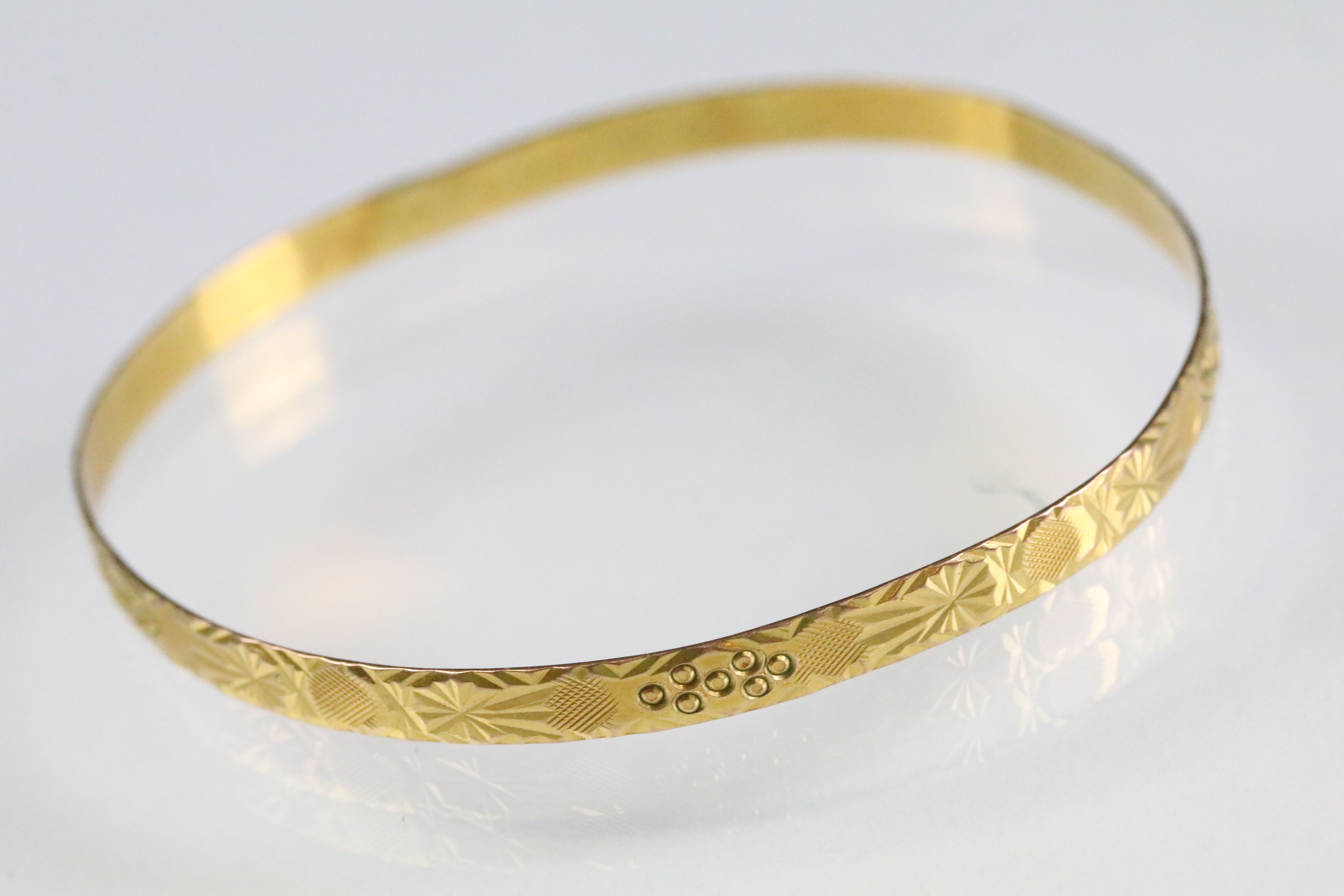 Incised closed bangle bracelet with geometric details. Yellow metal marked 22. Measures 6cm wide.