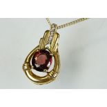 9ct gold and garnet pendant being set with an oval cut ruby within a gold mount with accent stones