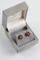 Pair of 9ct gold ruby and diamond cluster earrings. The earrings set with a round cut diamond to the