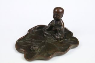 A Chinese bronze burner in the form of a praying monk on leaf.