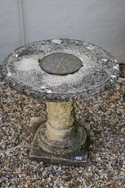 Reconstituted stone round top garden table with metal plaque to centre, raised upon a support with