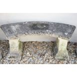 Stone garden seat of curved form, raised on two supports with floral decoration in relief, approx