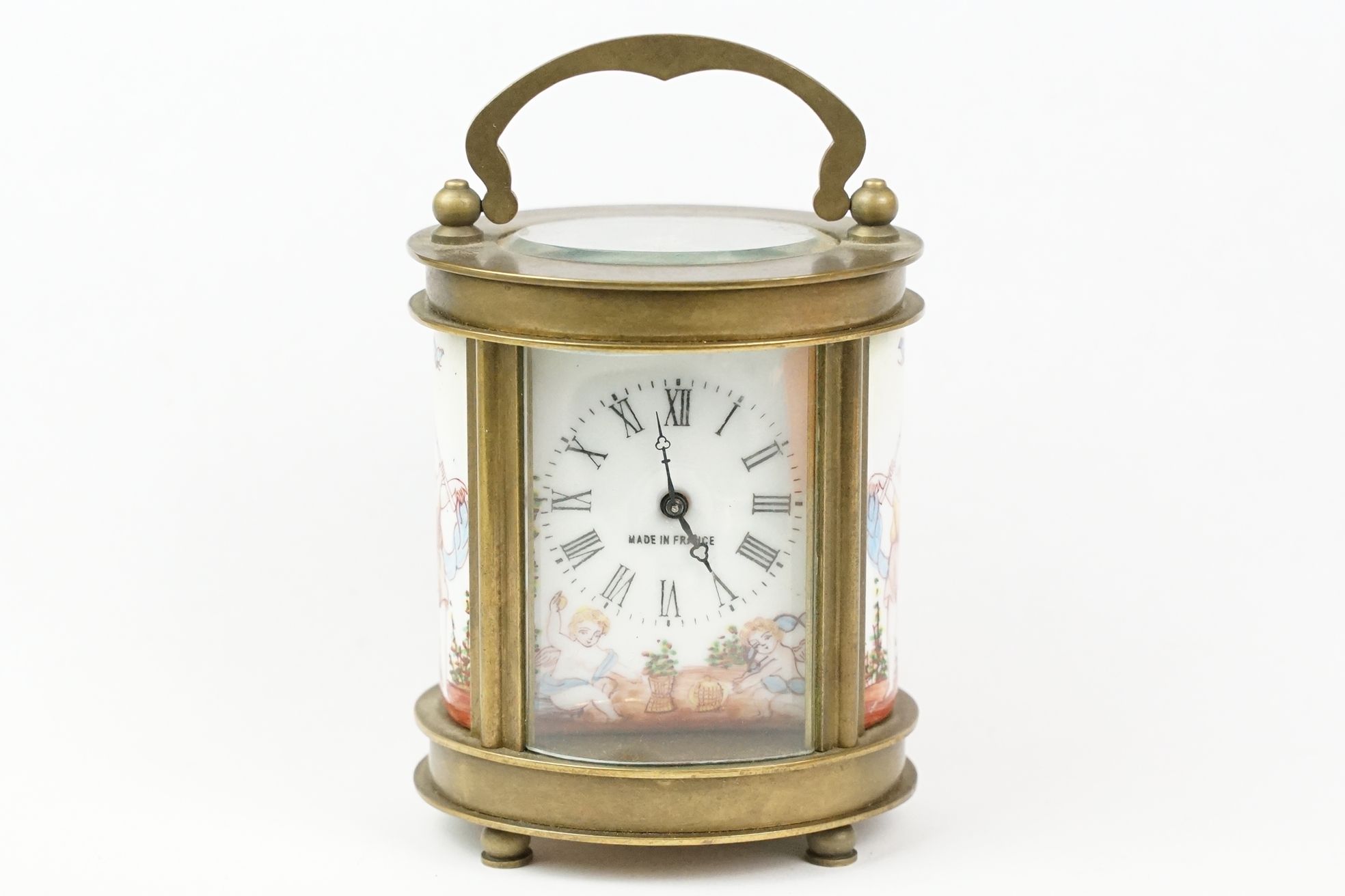 An antique French miniature carriage clock, brass cased with beveled glass panels, decorative Cherub