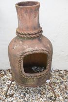 Terracotta patio chimenea, raised on three scrolled wrought iron supports, approx 109cm tall