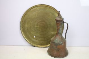 Large antique Eastern copper jug, together with a large brass charger with bands of repeating