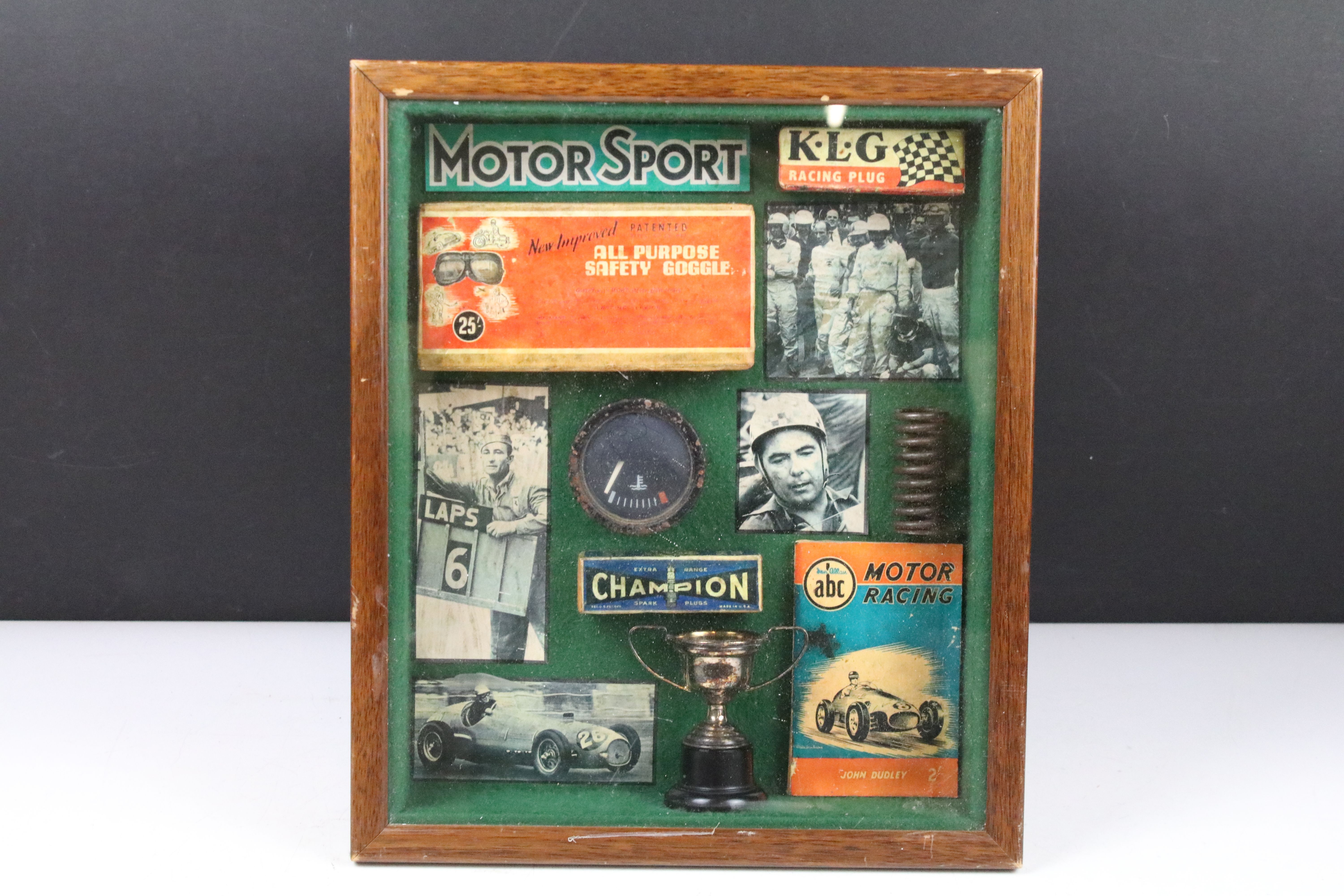 A small group of Motor Racing collectables within a fitted display case.