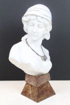 Ceramic bust of a female with pensive expression, wearing a silver necklace, raised on a marble