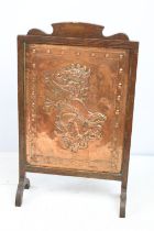 Early 20th century fire screen, the embossed copper panel decorated with a lion rampant, with oak