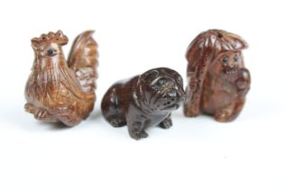 Three Chinese carved wooden netsuke in the form of a Monkey, dog and cockerel.