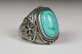 A silver ladies dress ring with central turquoise cabochon and floral decoration, marked 925 to
