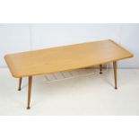 Mid century coffee table with rack to underside on tapering legs with metal feet, 35cm high x