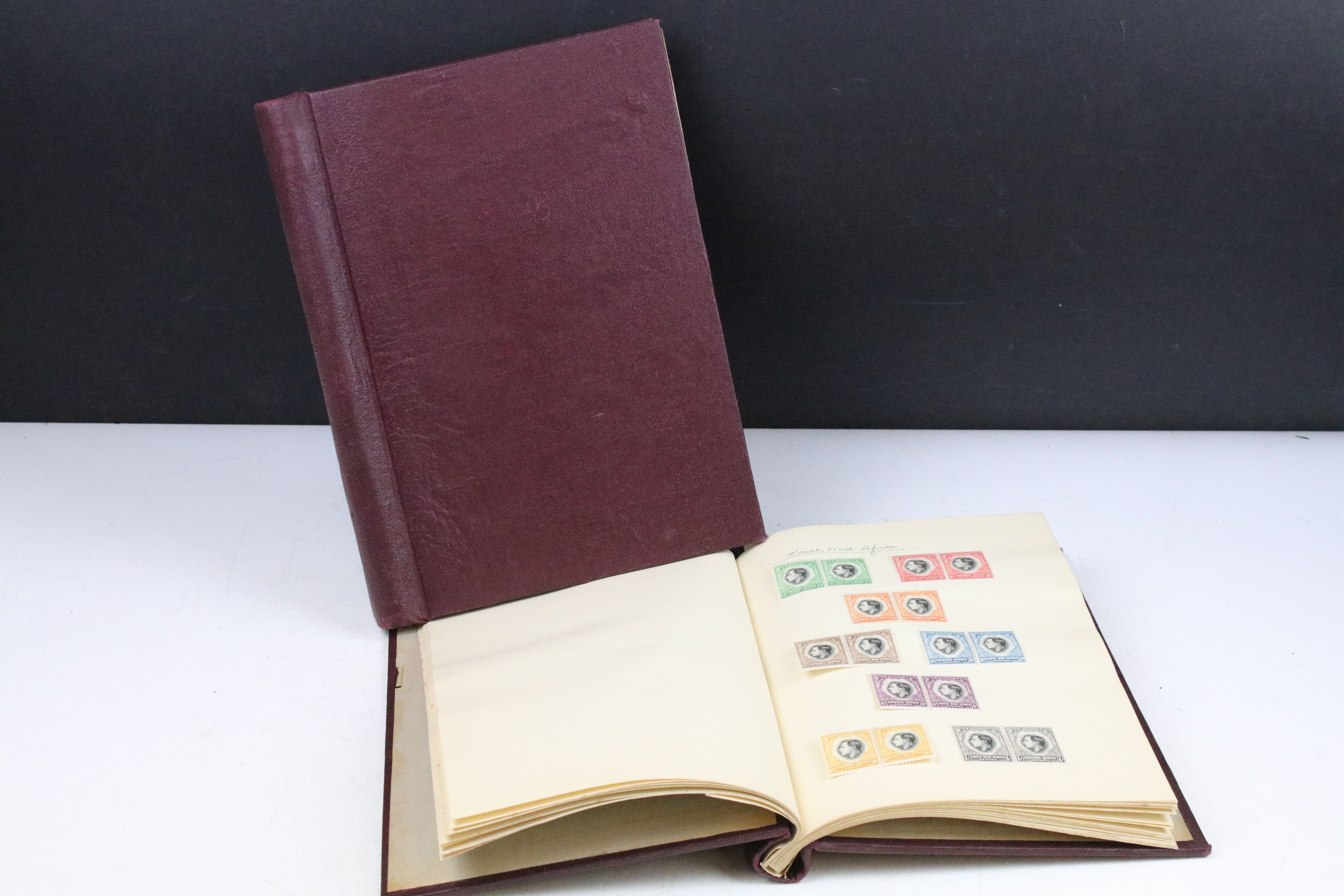 A stamp album containing stamps marking the silver jubilee of King George V from the UK and