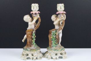 Pair of 19th century Continental porcelain candlesticks modelled with putti, with blue crossed