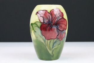 Moorcroft Hibiscus pattern vase having a cream ground with pink flower to front. Original sticker to