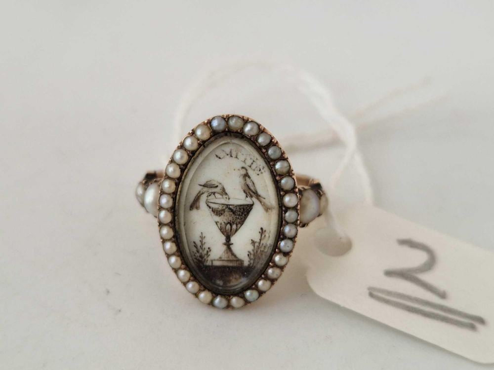 A George III ring with bird and urn motif within a pearl border set in gold