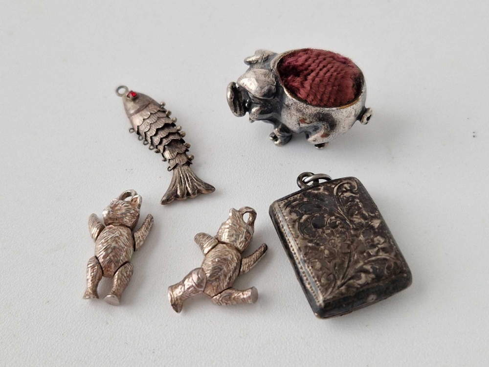 A miniature silver pig pin cushion together with four other silver charms