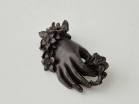 A large Victorian mourning brooch of hand holding flowers
