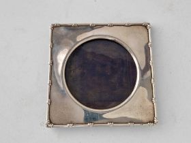 A square photo frame with decorated rim and circular aperture, 5 inches high, London 1906 by WC