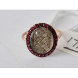 A gold mid 18th century oval memorial gold ring with plaited hair centre garnet boarder dated 1769