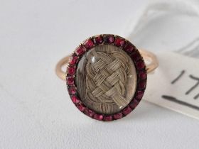 A gold mid 18th century oval memorial gold ring with plaited hair centre garnet boarder dated 1769