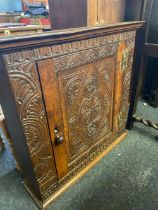 An antique carved oak hanging cupboard with brass hinges 32 in wide