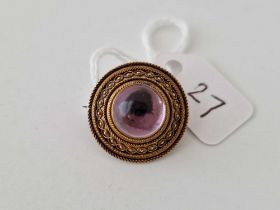 A antique Victorian Etruscan brooch set with a cabochon amethyst