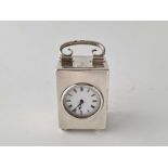 A small silver cased travelling clock with circular aperture and swing handle, 3.5 inches high,