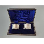 A pair of boxed napkin rings, plain except for wavy edges, Birmingham 1908, 42 g