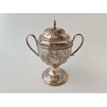 A George III two handled cup and cover embossed with figures and scrolls, reeded rims, 7 inches