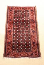 An Antique Caucasian Rug woven with a trellis of floral motifs on a dark in a salmon pink ground