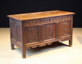 A 16th Century Style Carved Oak Coffer. The triple panel lid in a moulded frame.