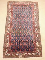 An Antique Caucasian Carpet with repeated design on a blue ground in a triple banded border