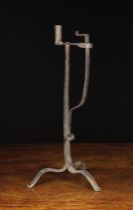 A Wrought Iron Tripod Peerman with candle socket and sprung rush jaw on a tapered square section