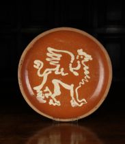 A Late 19th/Early 20th Century Red Earthenware Dish slip glazed with a winged griffin,