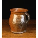An 18th Century Glazed Red-ware Pottery Jug with an incised band to the bulbous body and a strap