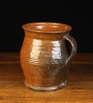 An 18th Century Glazed Red-ware Pottery Jug with an incised band to the bulbous body and a strap