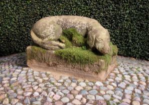 A 19th Century Stone Carving of a Recumbent Dog on a rectangular base, 11½" (29 cm) high,