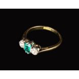 An 18 Carat Gold Ring set with an emerald flanked by two brilliant cut diamonds.
