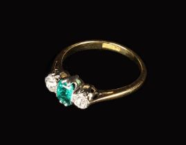 An 18 Carat Gold Ring set with an emerald flanked by two brilliant cut diamonds.