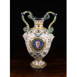 A Large Maiolica Pedestal Foot Urn with scrolling twin serpentine handles and releif moulded face