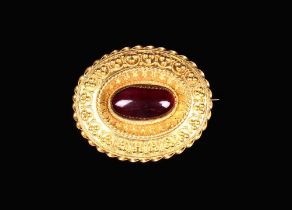 A Victorian Pinchbeck Locket Brooch set with a Cherry Amber cabochon within a decorative surround