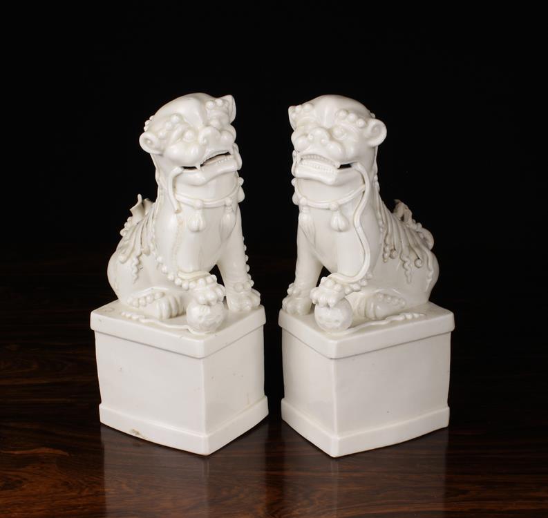 A Pair of Late 19th Century Blanc de Chine Porcelain Dogs of Fo on rectangular plinths,