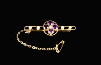 A 15 Carat Gold Bar Brooch set with a quatrefoil of amethysts and seed pearls and fitted with a