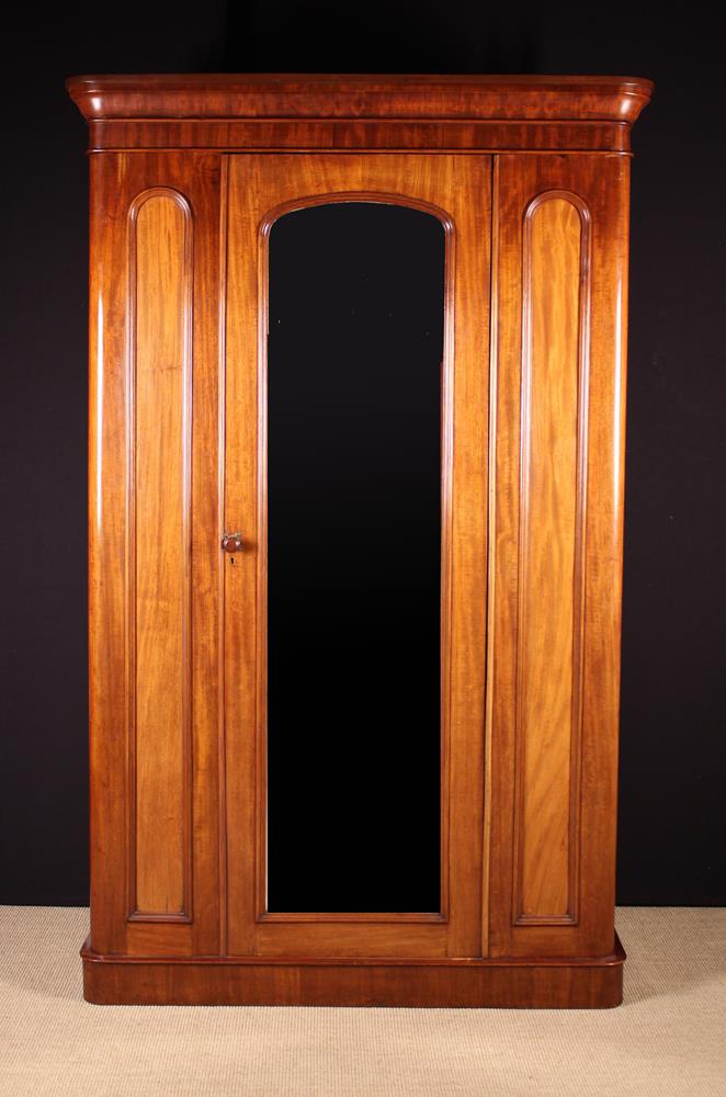 A Victorian Mahogany Wardrobe with moulded cornice above a full length arch-topped mirror panelled