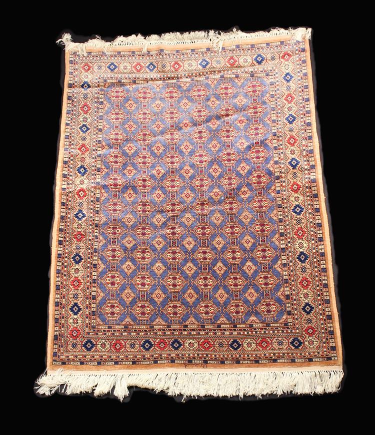 A Signed Pakistani Rug woven in silky threads of predominantly red and blue with repeated geometric